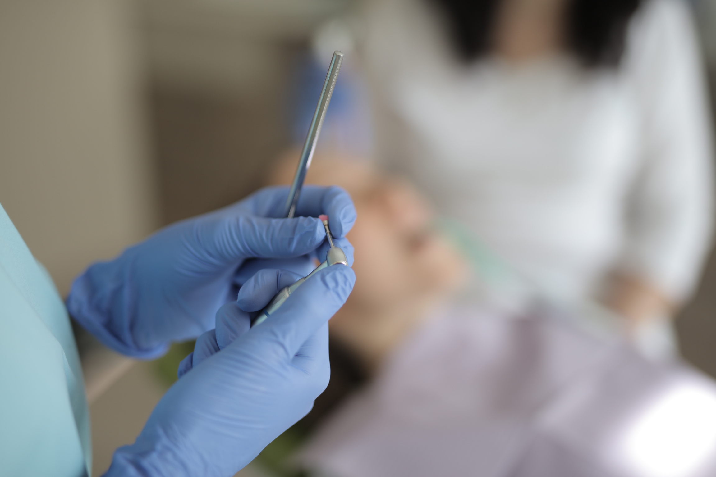 Unrecognizable crop dentist holding instruments in hands while working in clinic